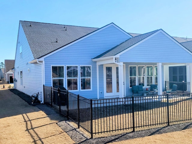 view of front of home featuring roof with shingles, a patio area, and fence private yard