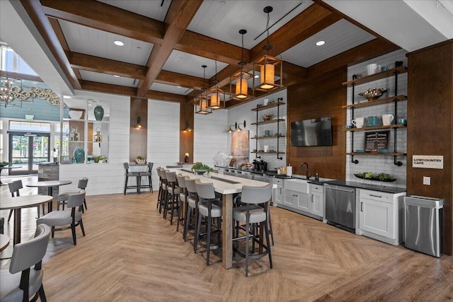 dining room featuring a notable chandelier, wooden walls, coffered ceiling, and beamed ceiling