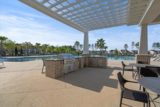 view of patio with exterior kitchen, a grill, a community pool, and a pergola