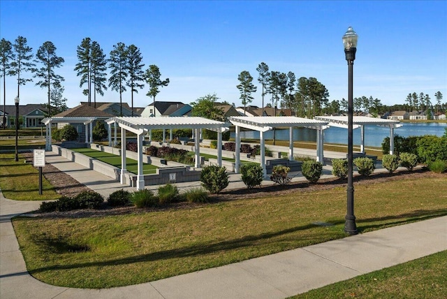 view of property's community featuring a water view, a yard, and a pergola