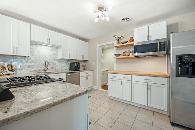 kitchen with visible vents, a sink, wooden counters, stainless steel appliances, and open shelves