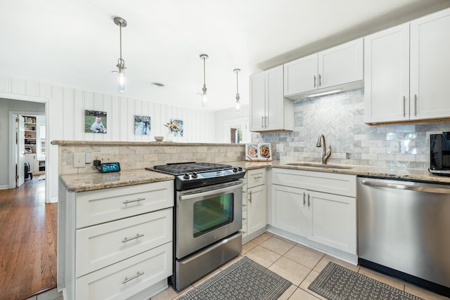 kitchen with a sink, tasteful backsplash, white cabinetry, stainless steel appliances, and a peninsula