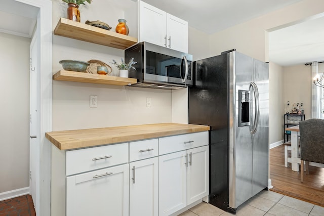 kitchen with open shelves, light tile patterned flooring, appliances with stainless steel finishes, white cabinetry, and butcher block counters