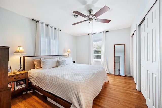 bedroom featuring ceiling fan, visible vents, baseboards, and wood finished floors