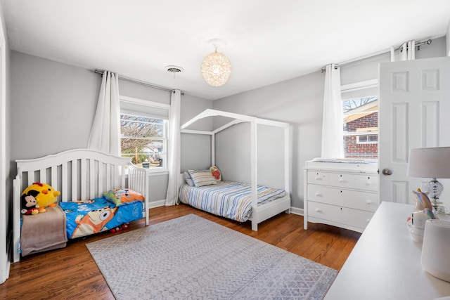 bedroom featuring wood finished floors, visible vents, and baseboards