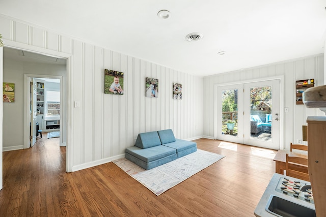 living area with visible vents, baseboards, wood finished floors, and french doors