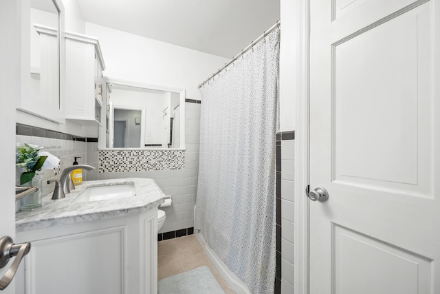 bathroom with toilet, tile walls, vanity, and tile patterned flooring