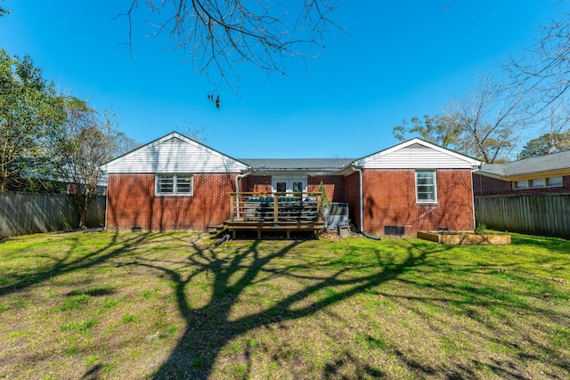 rear view of house featuring a wooden deck, brick siding, a fenced backyard, and a lawn