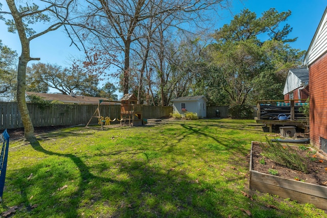 view of yard with a garden, a storage unit, an outbuilding, and a fenced backyard