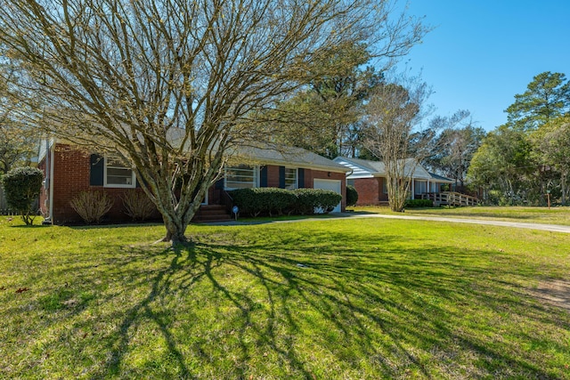 view of front of home with a front yard, brick siding, and a garage