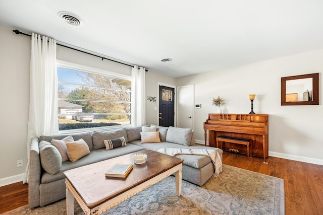 living room featuring wood finished floors, visible vents, and baseboards