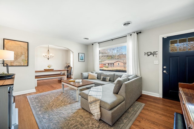 living room with visible vents, wood finished floors, arched walkways, and baseboards