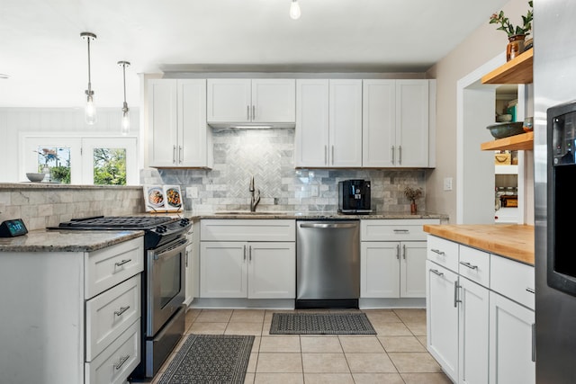 kitchen with light tile patterned floors, white cabinets, appliances with stainless steel finishes, and a sink