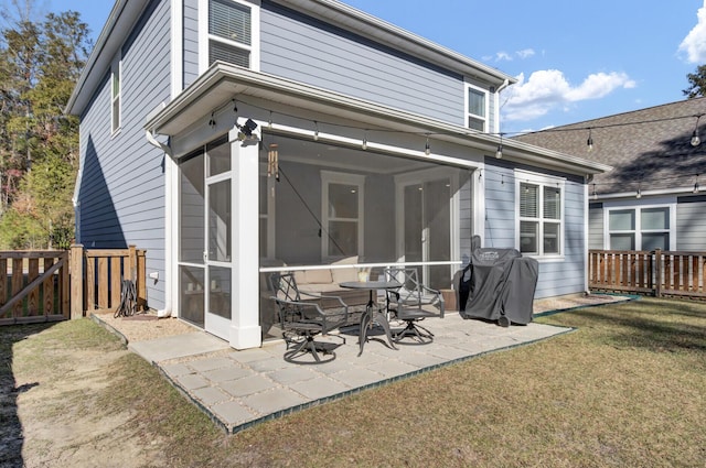 rear view of house featuring a lawn, a patio area, and a sunroom