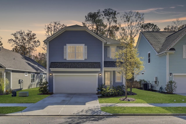 view of front of property with cooling unit, a garage, and a yard