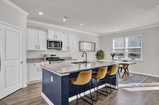 kitchen with sink, hardwood / wood-style floors, a center island with sink, white cabinets, and appliances with stainless steel finishes