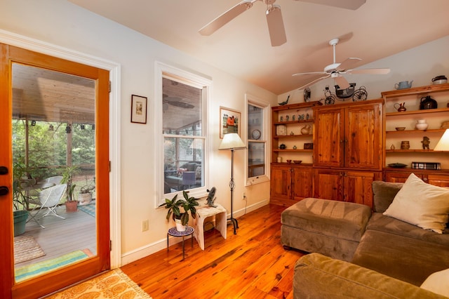 living area with ceiling fan, light wood-style floors, baseboards, and vaulted ceiling