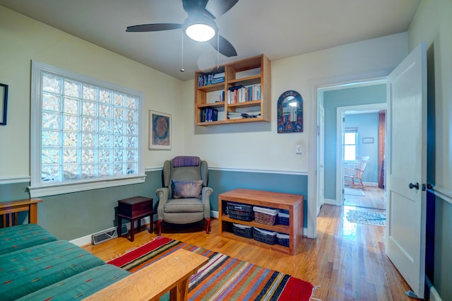 living area featuring wood finished floors, a ceiling fan, and baseboards