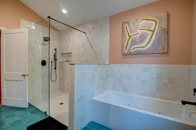 bathroom featuring tile patterned floors, a whirlpool tub, a walk in shower, lofted ceiling, and tile walls