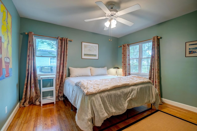 bedroom with multiple windows, baseboards, and wood finished floors