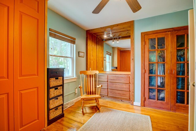 living area featuring light wood finished floors, ceiling fan, baseboards, and rail lighting