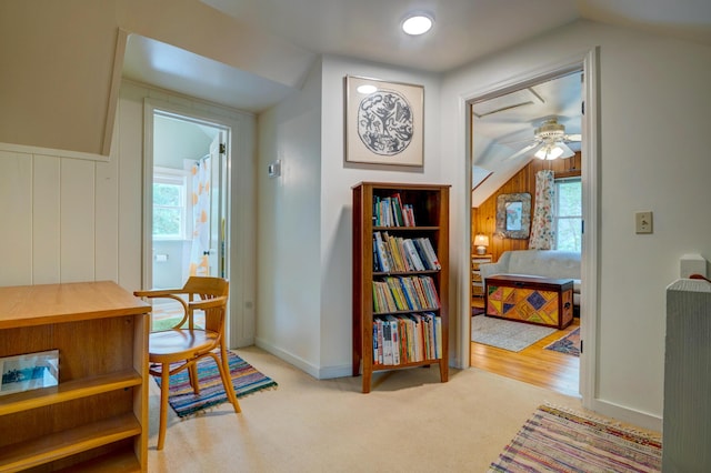 living area featuring lofted ceiling, a ceiling fan, healthy amount of natural light, carpet, and baseboards