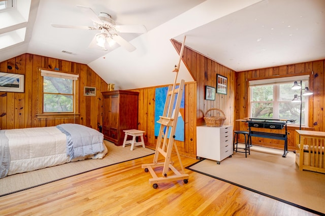 bedroom featuring multiple windows, wood walls, lofted ceiling, and wood finished floors