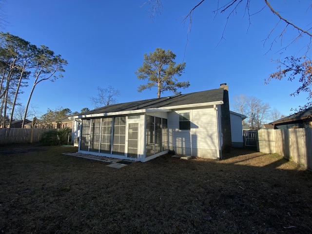 rear view of house featuring a yard and a sunroom