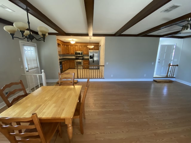 dining room featuring dark wood-type flooring, beamed ceiling, and an inviting chandelier