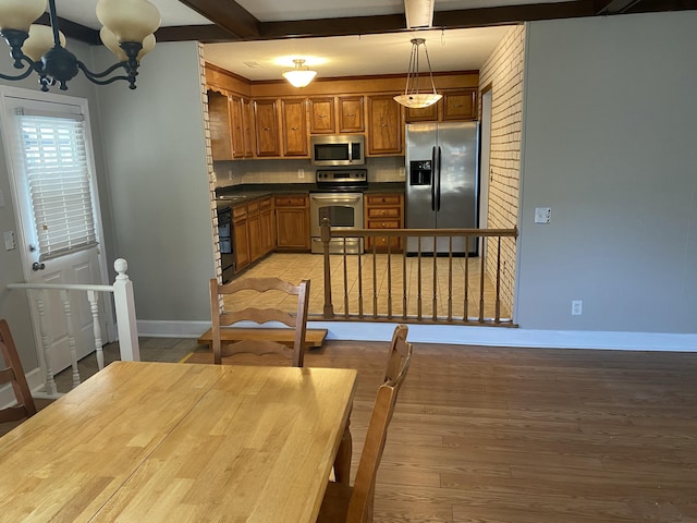 kitchen with a chandelier, light wood-type flooring, pendant lighting, backsplash, and stainless steel appliances