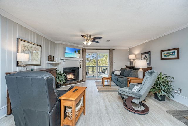 living room featuring light hardwood / wood-style floors, ceiling fan, a textured ceiling, and crown molding