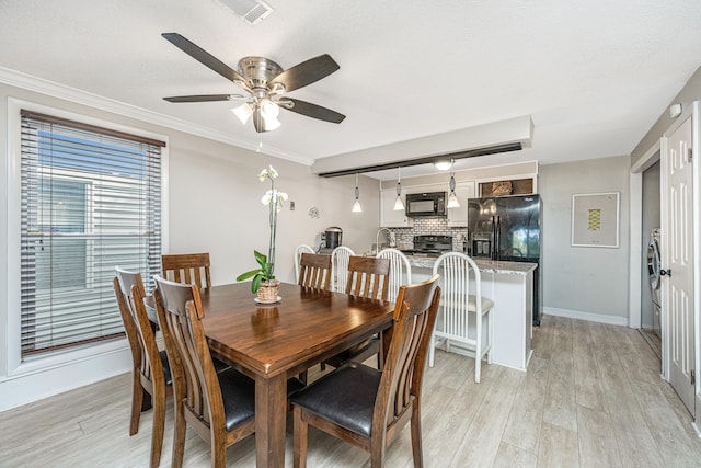 dining room featuring crown molding, a brick fireplace, ceiling fan, and light hardwood / wood-style flooring