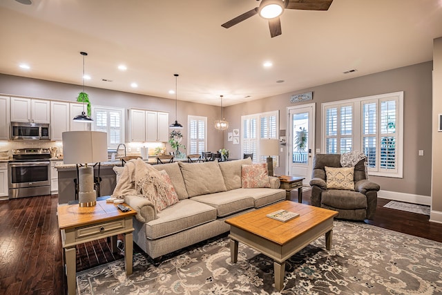 living room featuring ceiling fan with notable chandelier and dark hardwood / wood-style floors