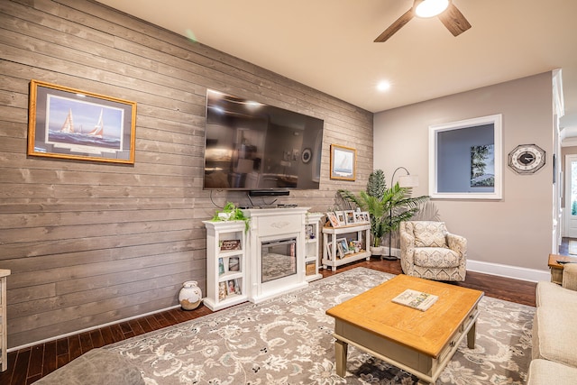 living room with wood walls, hardwood / wood-style floors, and ceiling fan