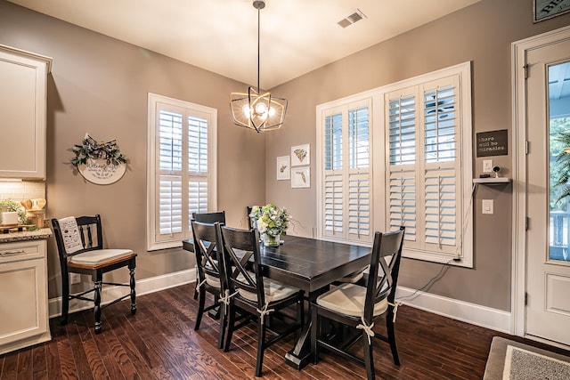 dining room with dark wood-type flooring and a chandelier