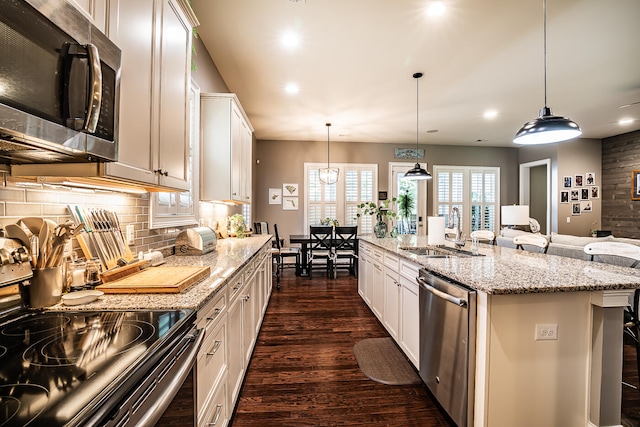 kitchen featuring appliances with stainless steel finishes, sink, an island with sink, dark hardwood / wood-style flooring, and decorative light fixtures