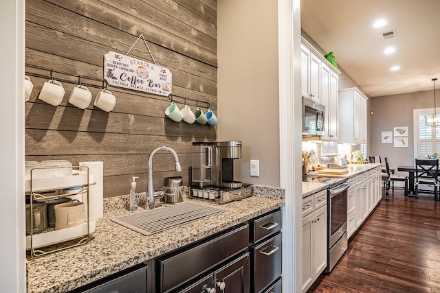 kitchen featuring dark wood-type flooring, stainless steel appliances, pendant lighting, white cabinets, and light stone counters