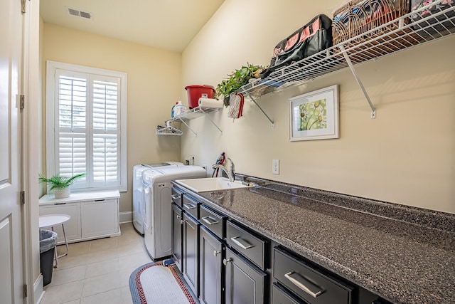 clothes washing area featuring sink, light tile patterned floors, cabinets, and washer and clothes dryer