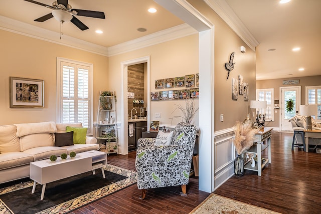 living room featuring dark wood-type flooring, ceiling fan, a healthy amount of sunlight, and ornamental molding