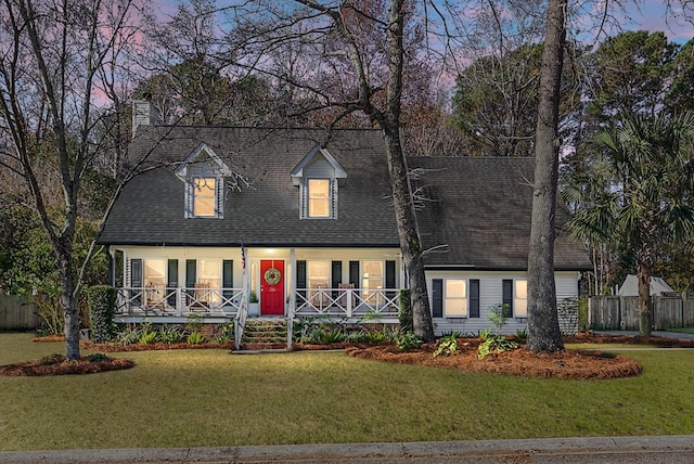 new england style home featuring a lawn and covered porch