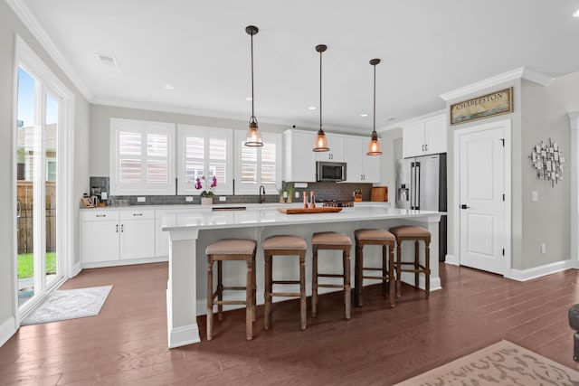 kitchen with white cabinetry, crown molding, decorative light fixtures, a center island, and appliances with stainless steel finishes