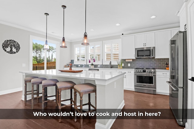 kitchen with pendant lighting, high quality appliances, white cabinets, ornamental molding, and a center island