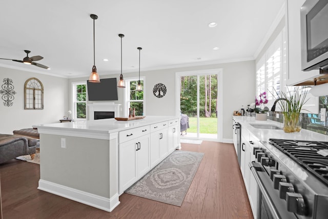 kitchen with appliances with stainless steel finishes, white cabinets, dark hardwood / wood-style flooring, a center island, and crown molding