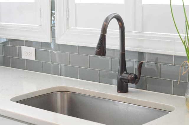 details with light stone countertops, sink, and backsplash