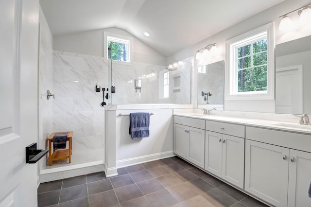 bathroom featuring vanity, vaulted ceiling, tile patterned floors, and a tile shower