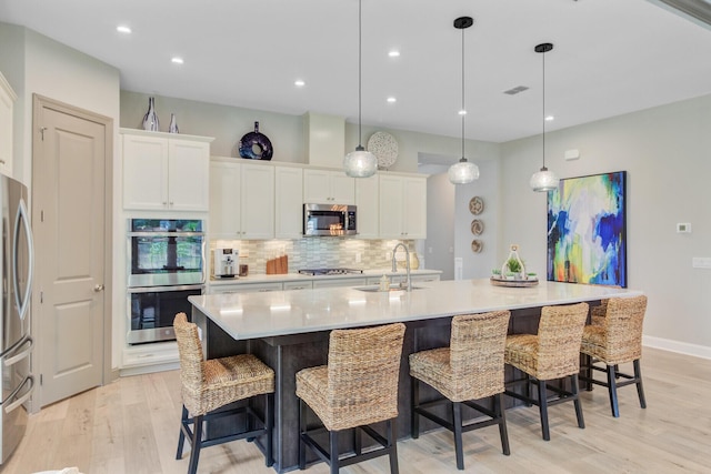 366 Tupelo Lake Dr, Summerville, SC 29486 - kitchen with stainless steel appliances, a sink, tasteful backsplash, light wood-style floors, and white cabinetry