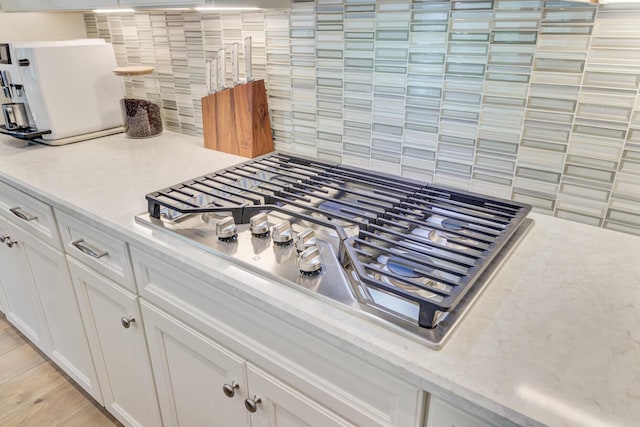 366 Tupelo Lake Dr, Summerville, SC 29486 - kitchen view of decorative backsplash, stainless steel gas cooktop, white cabinetry, and light wood-type flooring