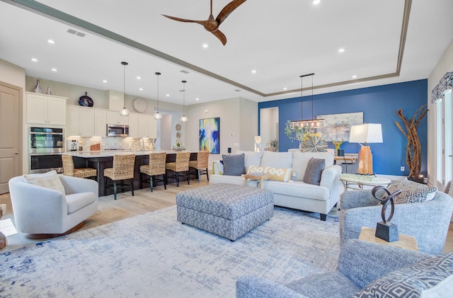 366 Tupelo Lake Dr, Summerville, SC 29486 - living room featuring recessed lighting, light wood finished floors, a raised ceiling, a ceiling fan, and a chandelier