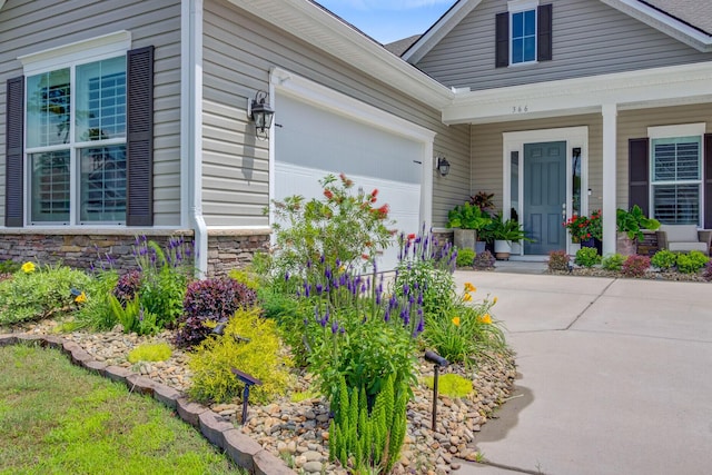 366 Tupelo Lake Dr, Summerville, SC 29486 - view of exterior entry featuring driveway, an attached garage, stone siding, and a porch
