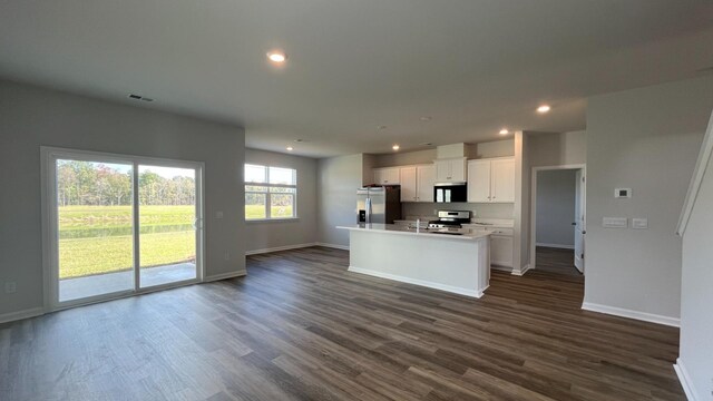 kitchen featuring white cabinets, a kitchen island with sink, appliances with stainless steel finishes, a breakfast bar area, and dark hardwood / wood-style flooring